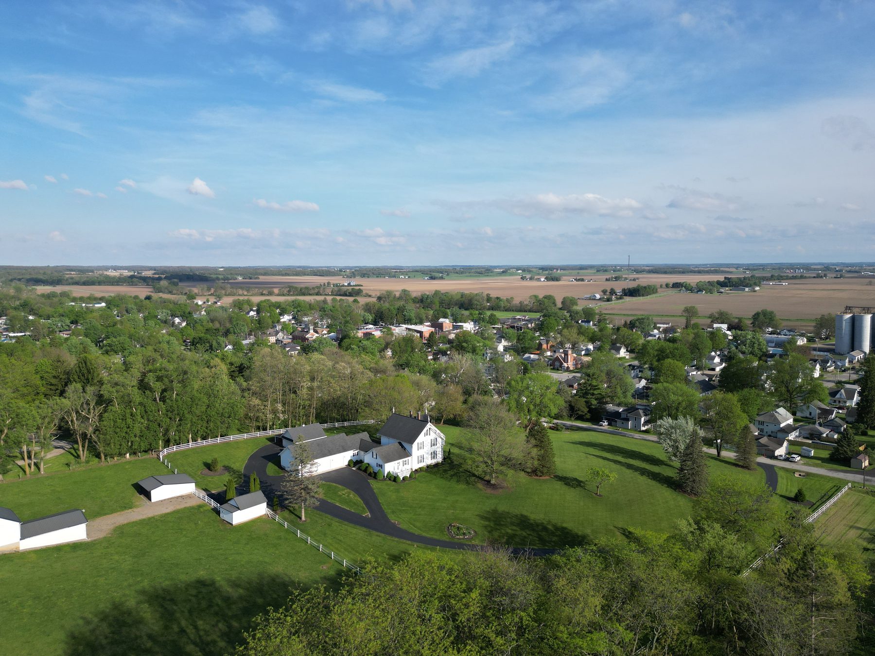 The edge of the village from the air, a farmstead and outbuildings with the village and grain elevator beyond