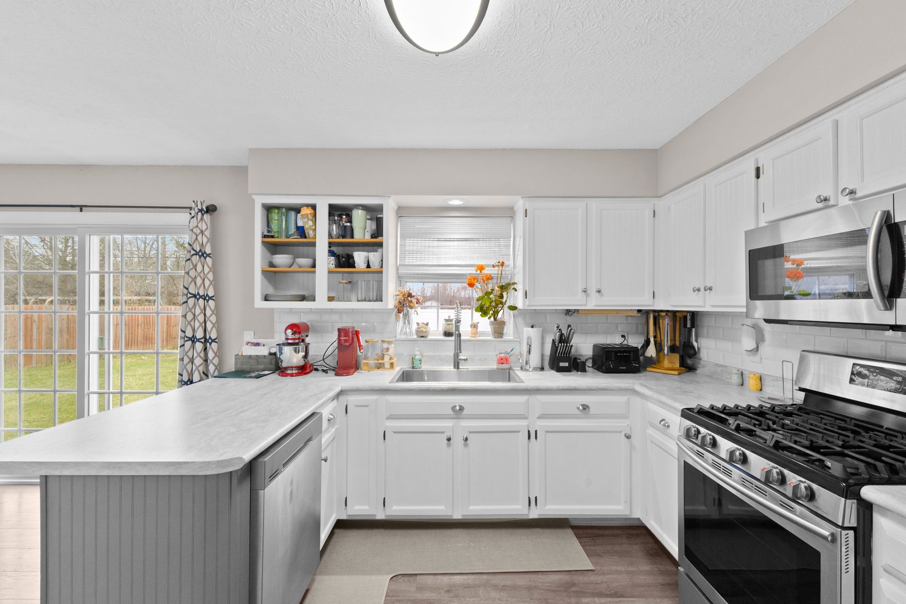 Kitchen from the other side, showing the peninsula counter, sink beneath the window and sliding doors to the yard