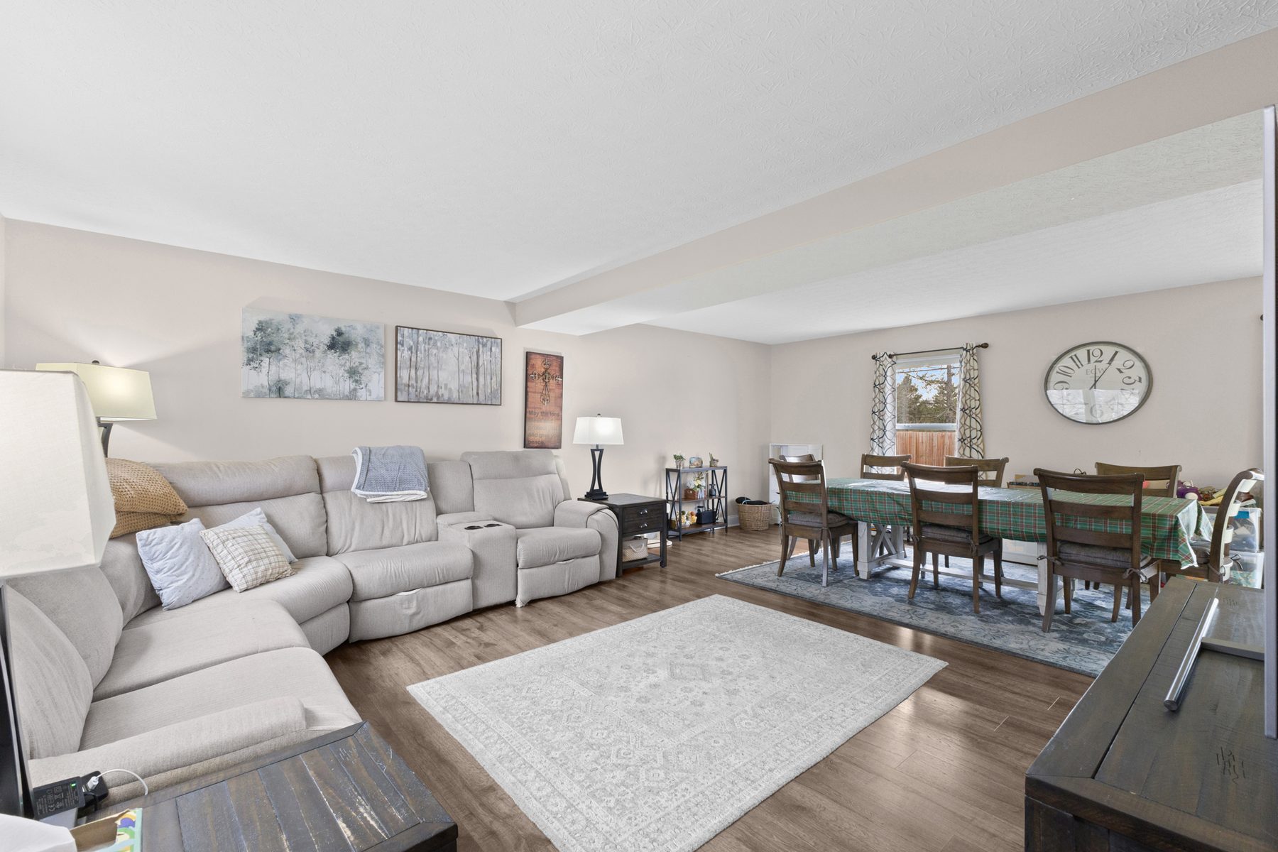 Living room with a light sectional sofa and an area rug, open through to the dining area beyond
