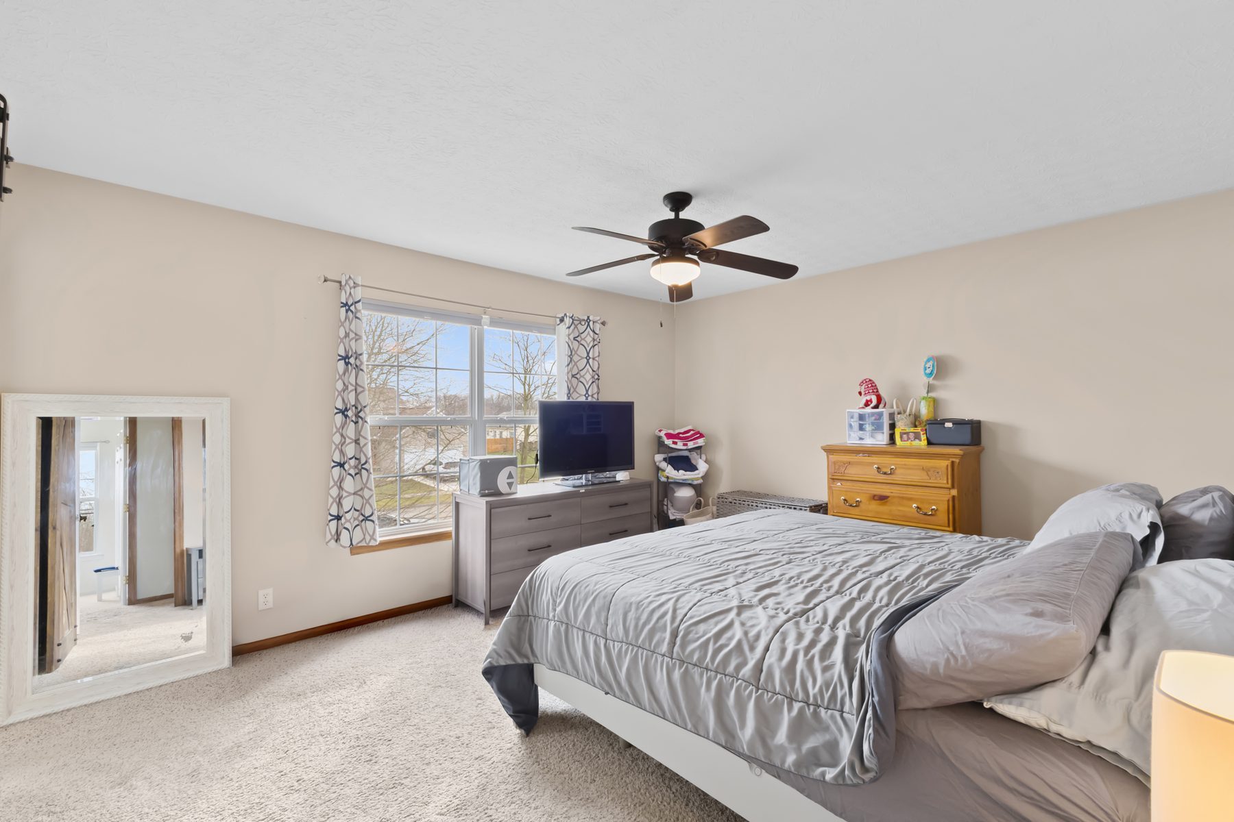 Bedroom with a bed, ceiling fan, carpeted floor and a window to the front yard