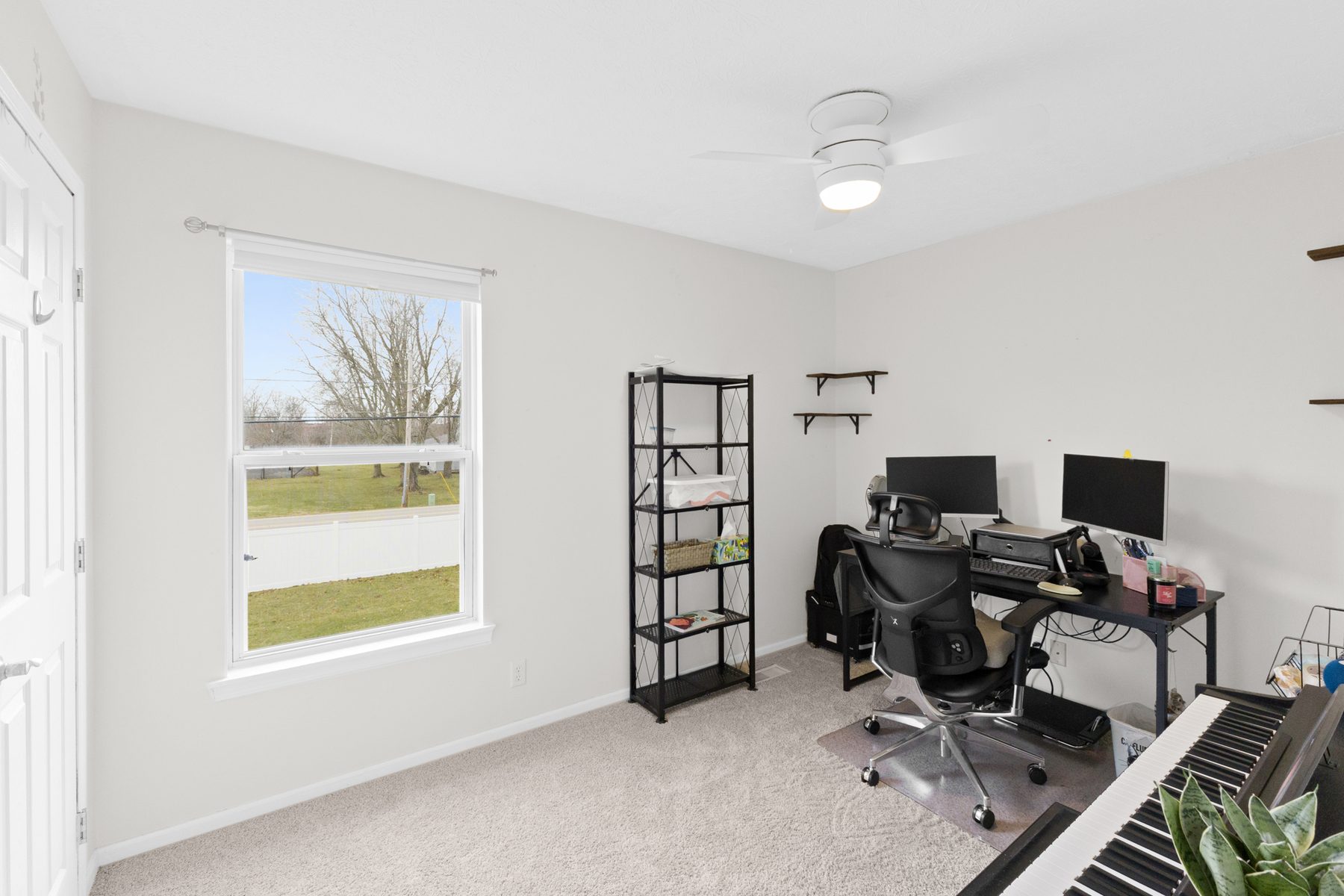 Flex room used as an office, with a desk and monitors, open shelving and a window to the yard