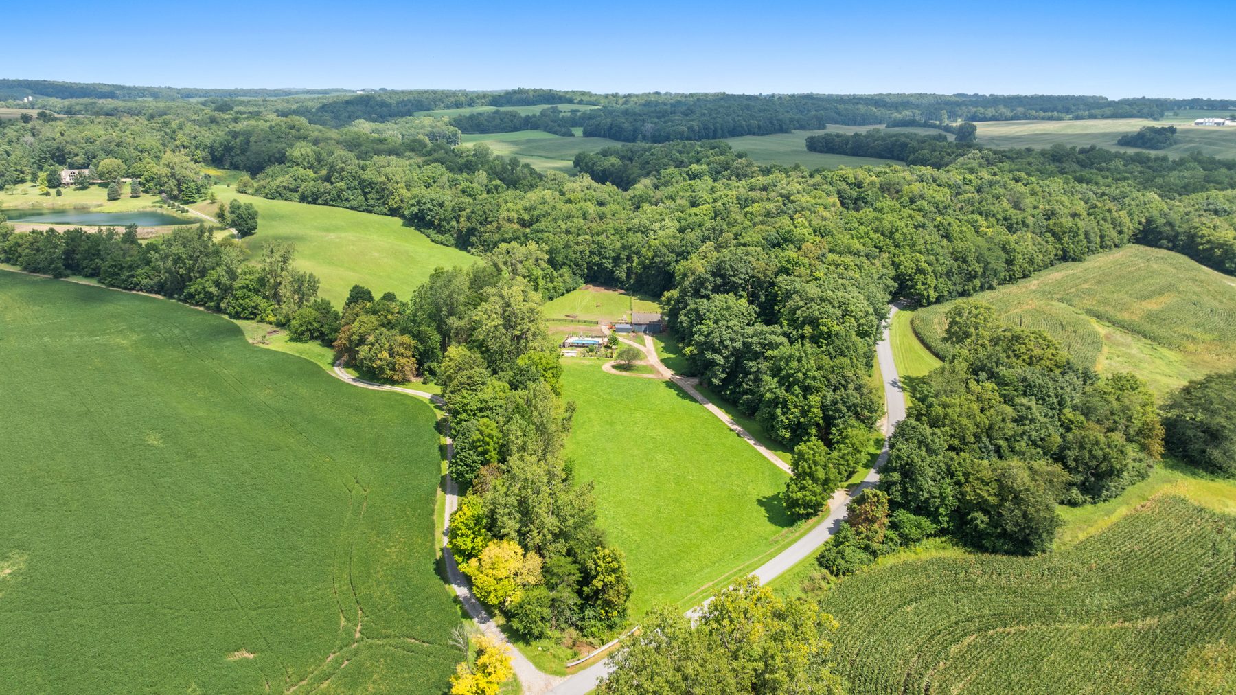 Aerial view of the cropland, woodland and rolling ground beyond the property's tree line