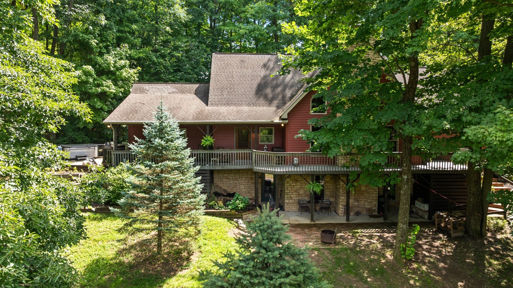 Fullest view of the house: red siding above a stone-faced walk-out lower level, with stacked decks across the back