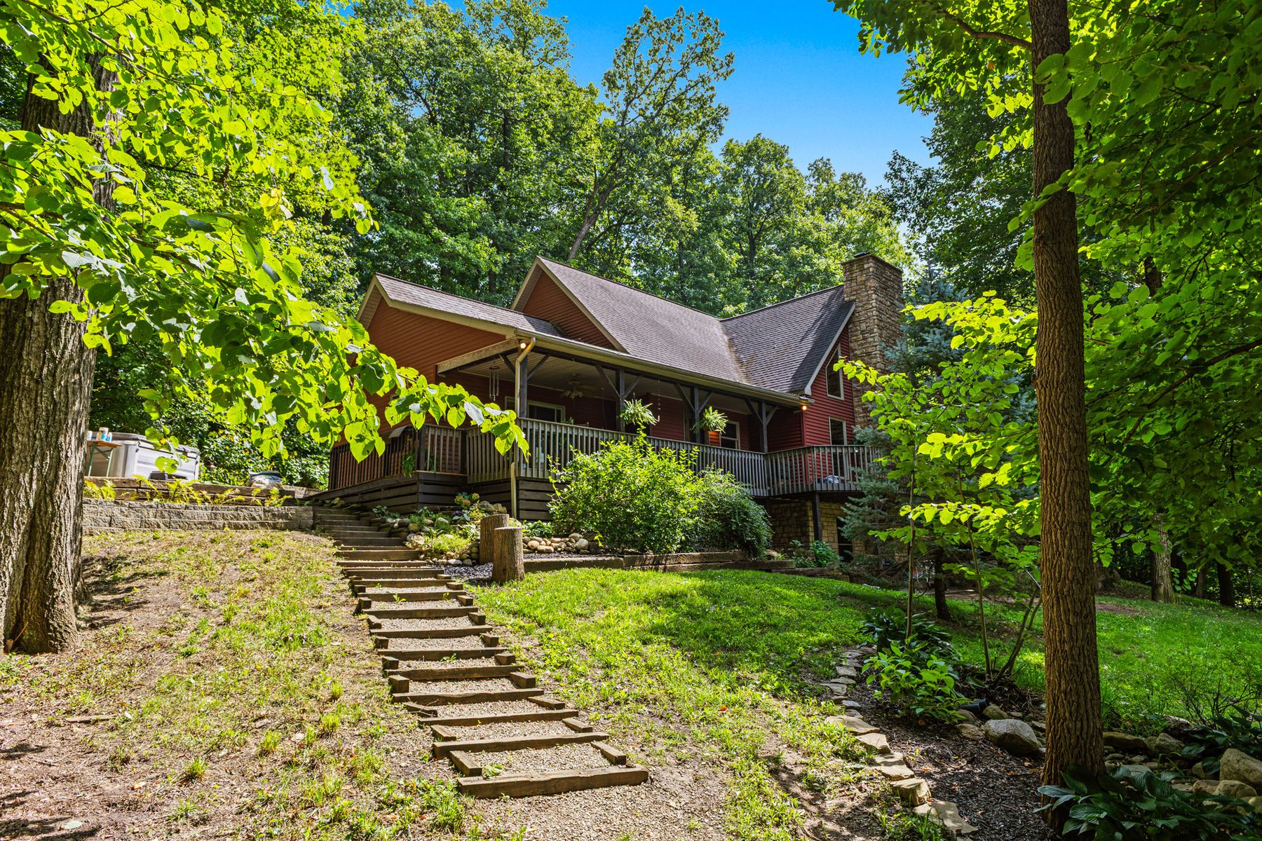 The house seen from the lawn, with a stone step path leading up to it through mature trees and open grass in the foreground