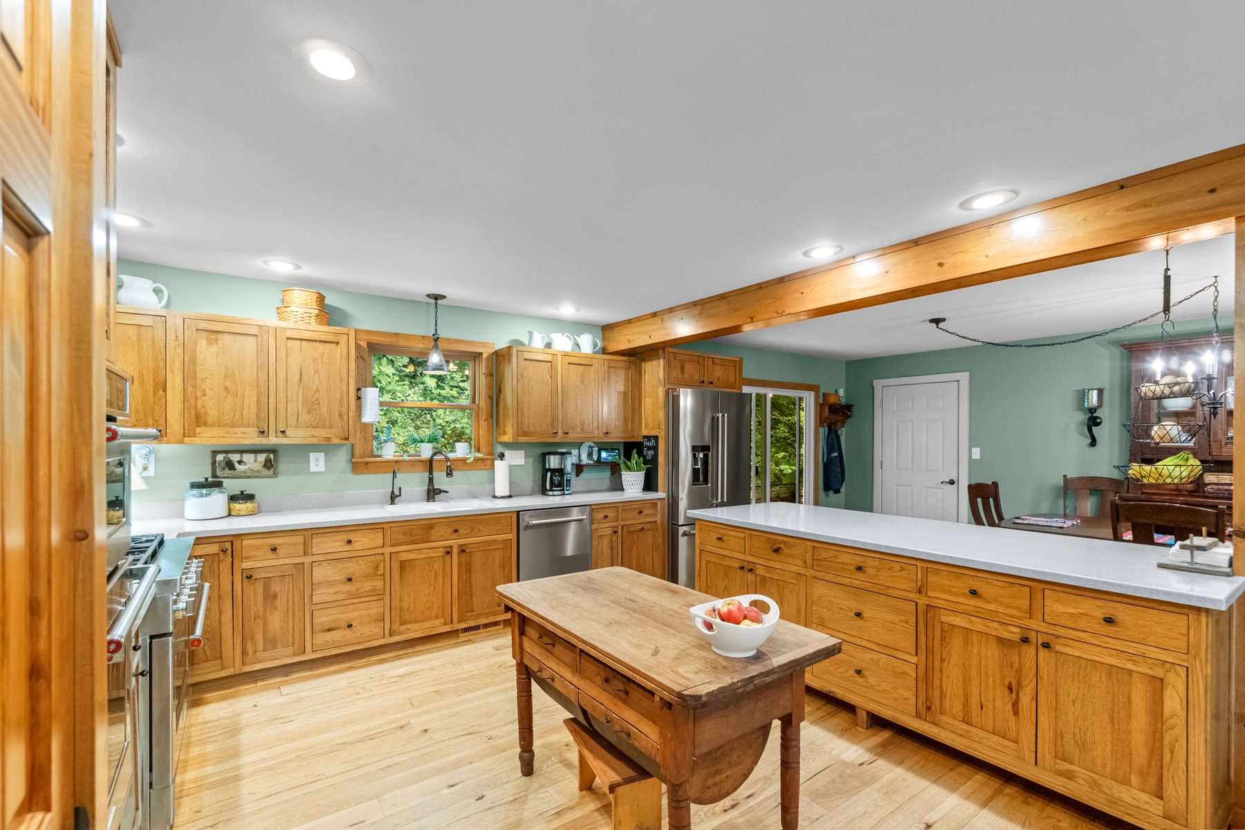 Kitchen with hickory cabinetry, a gas range, stainless dishwasher, island and a work table on wood floors