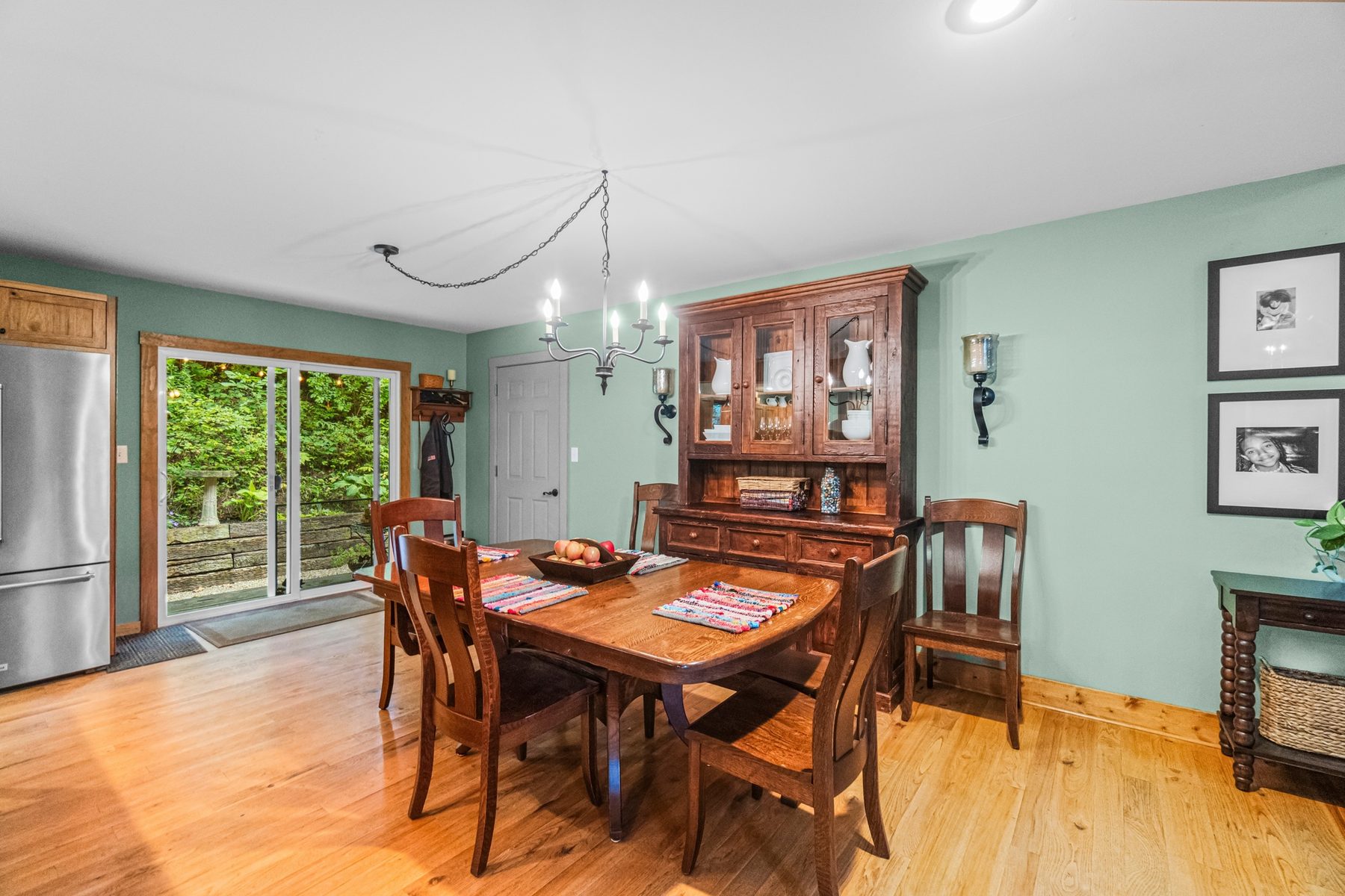 Dining area with a wood table and chairs, a chandelier, hutch and sliding doors out to the deck