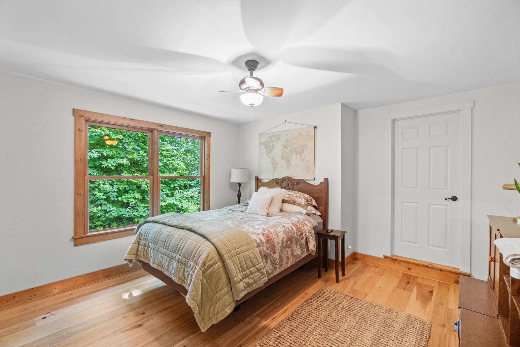 Bedroom with a ceiling fan, wood floor and a window looking into the trees