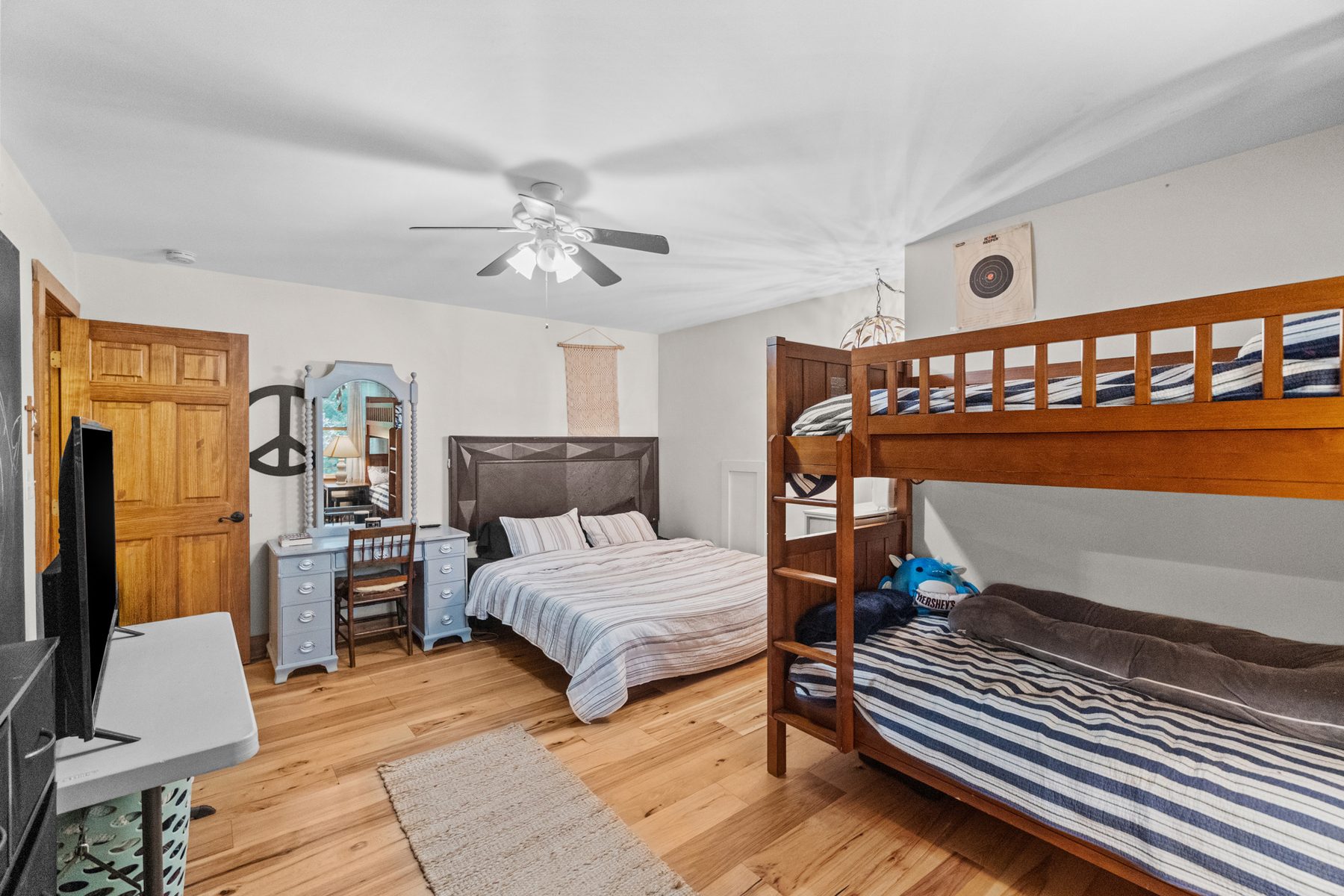 Bedroom with a bunk bed and a second bed, ceiling fan and wood flooring