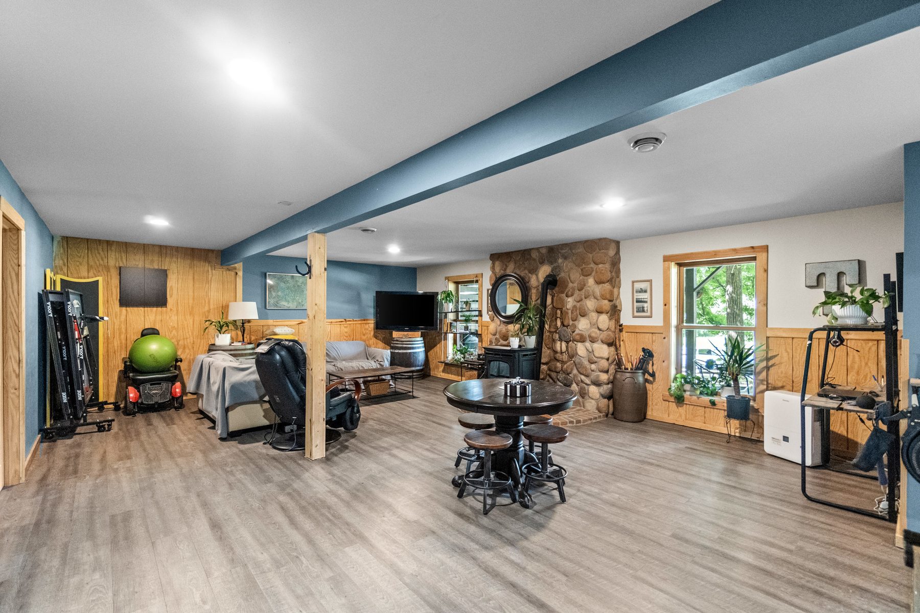 Finished lower level with a stone wall, wood-look flooring and room for seating and exercise equipment