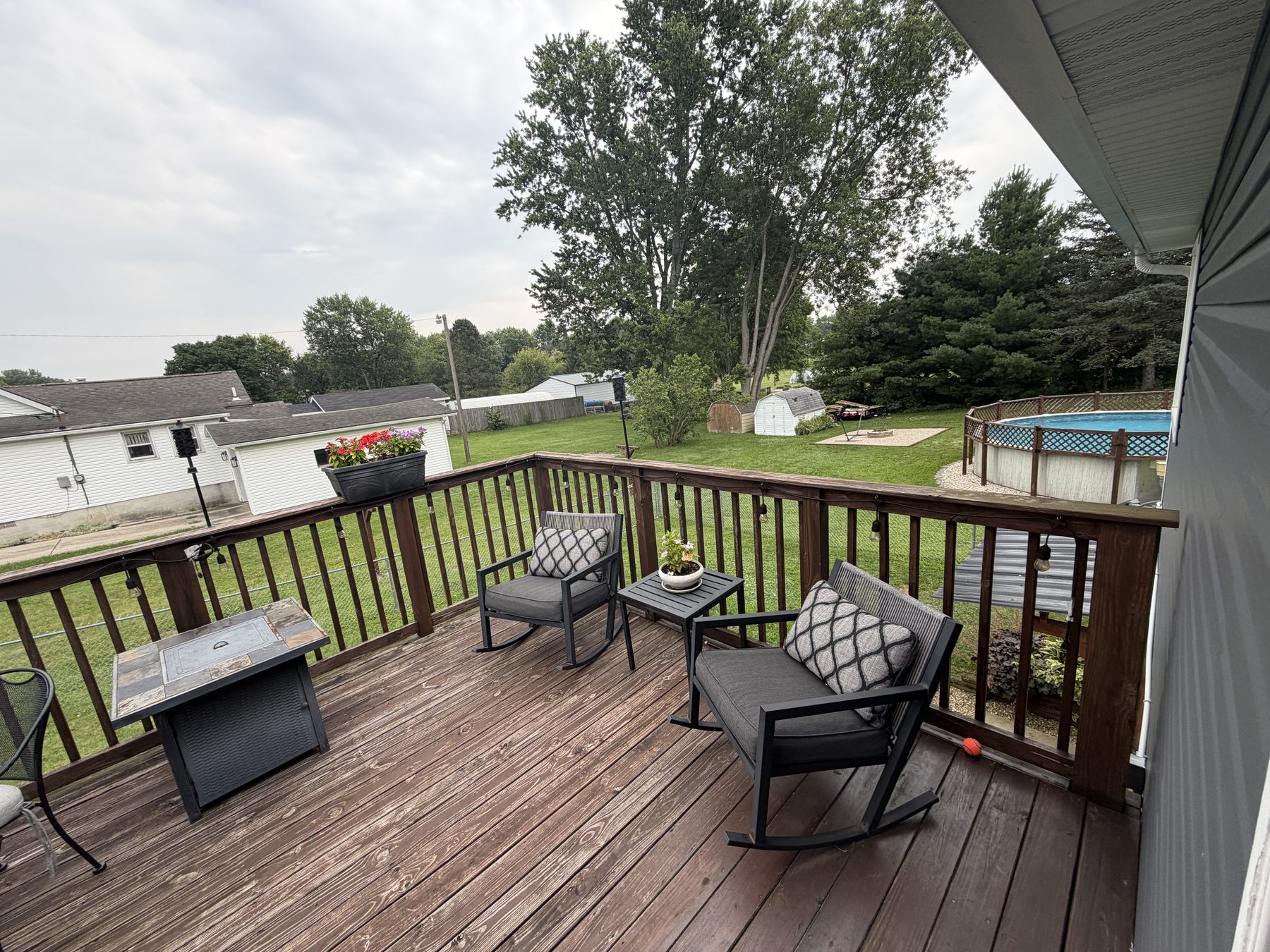 Back deck from the other end, with chairs and a side table looking out over the yard and neighbouring properties
