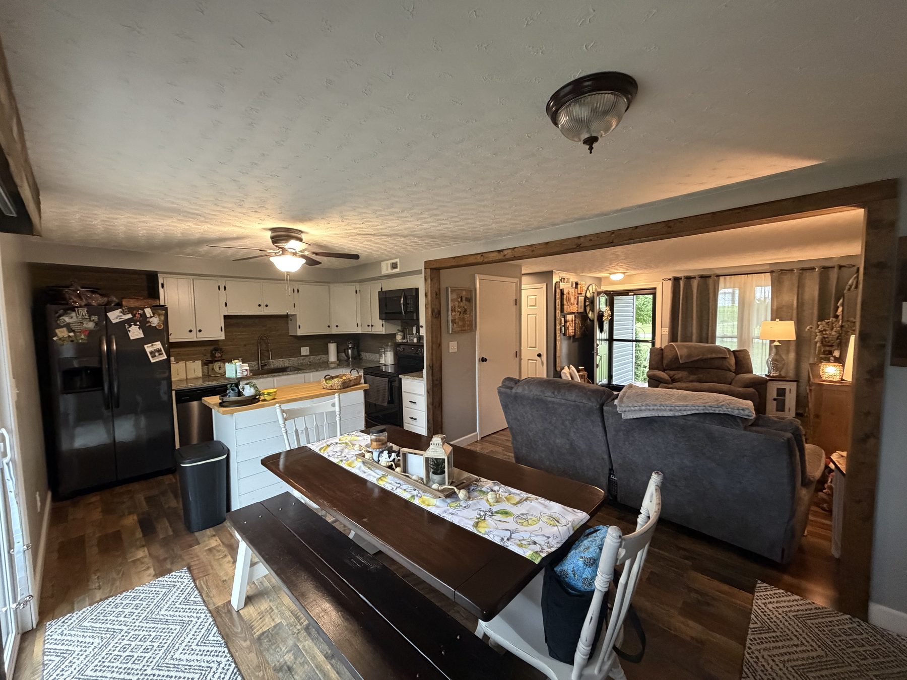 Dining area with a wood table and bench open to the kitchen on one side and the living room on the other