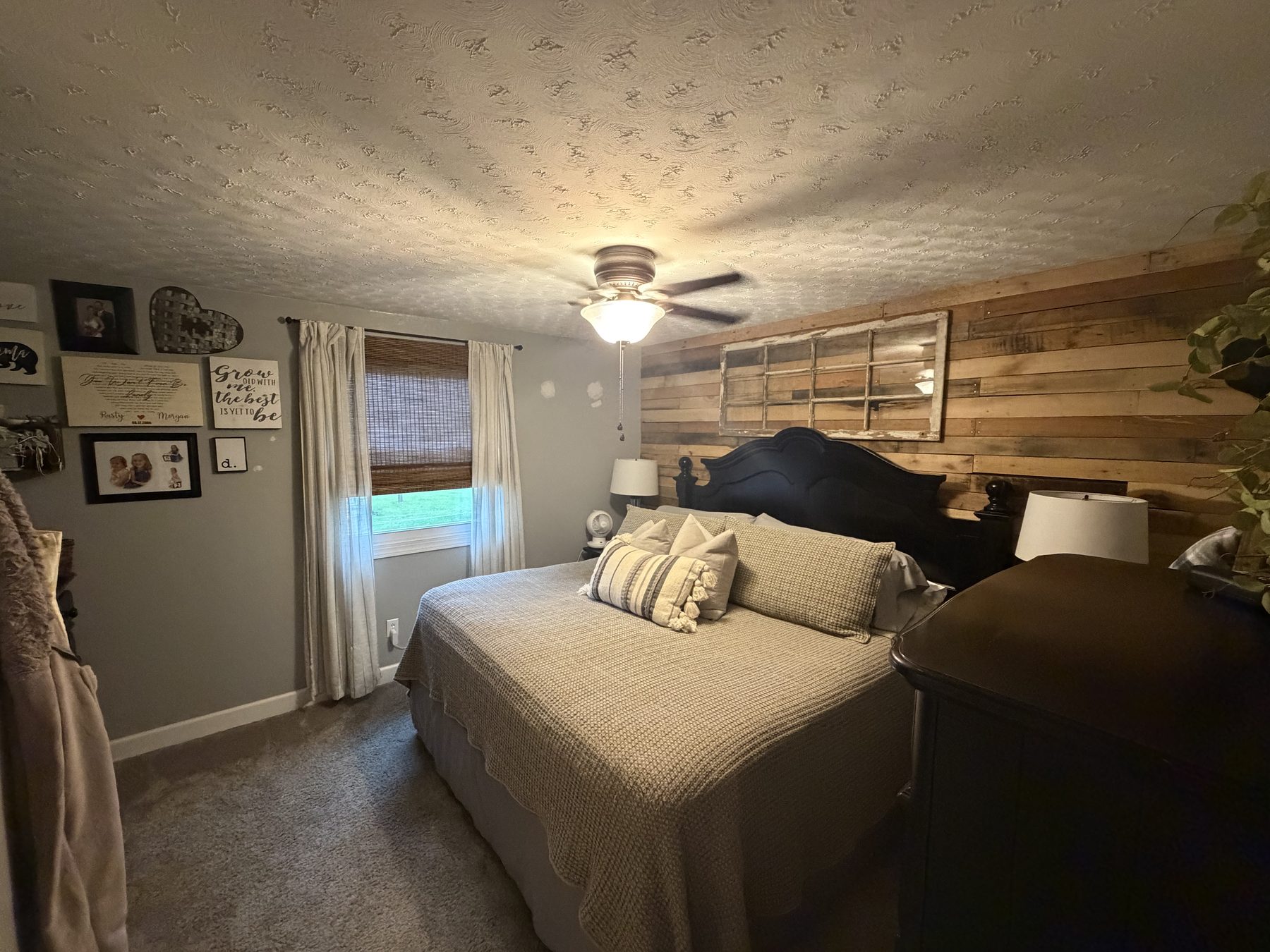 Bedroom with a wood plank accent wall, a ceiling fan and a curtained window