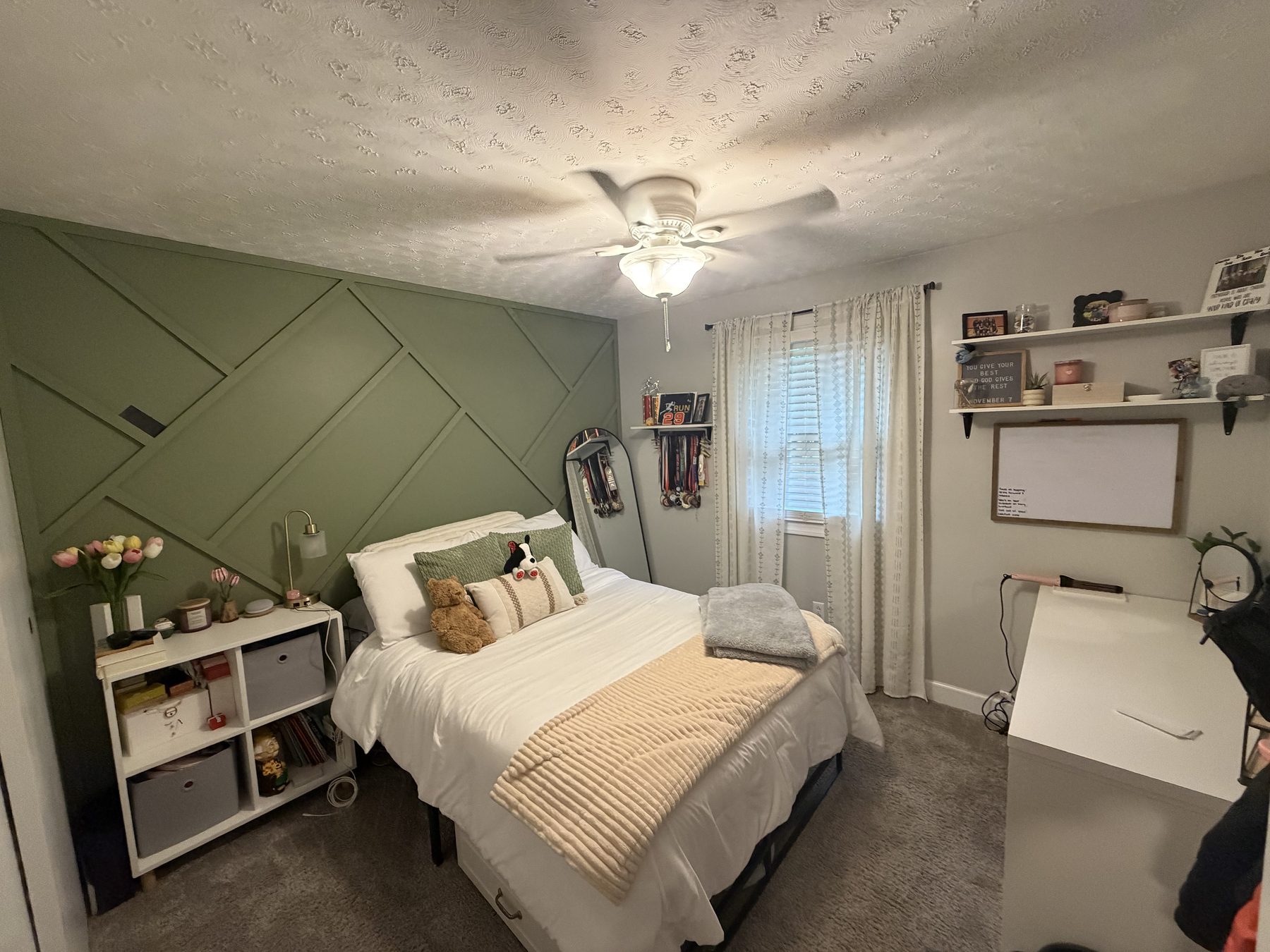 Bedroom with a green panelled accent wall, a ceiling fan, a curtained window and a desk in the corner