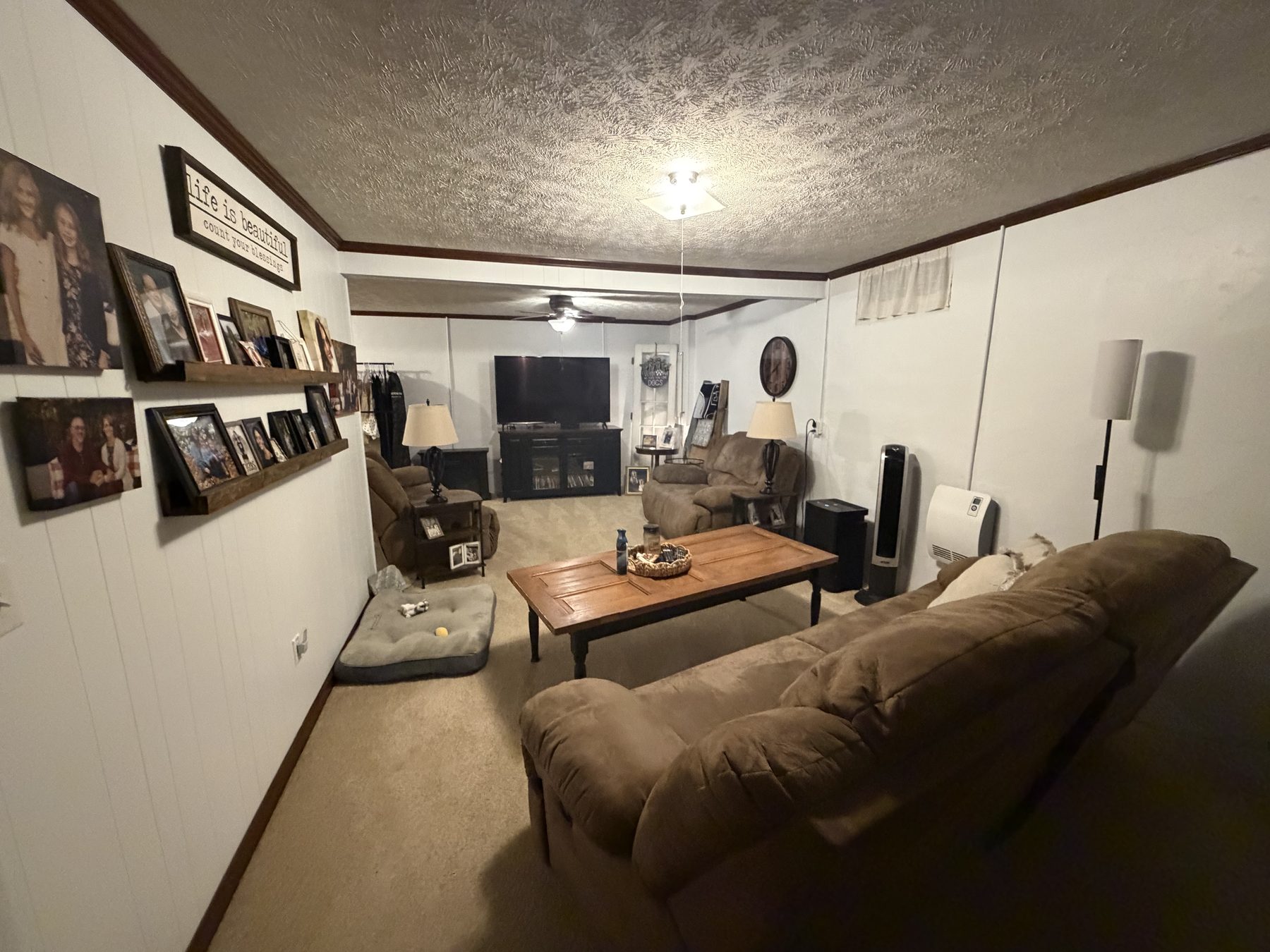 Second living room with a shiplap wall, framed photographs, seating and a coffee table